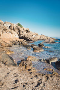 Rock formations in sea against clear blue sky