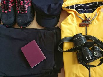 High angle view of camera with personal accessories and passport on table