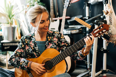 Portrait of a cheerful happy woman playing the acoustic guitar.