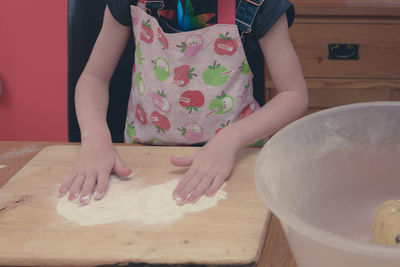 Midsection of girl kneading flour at home
