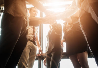 Business people stacking hands in brightly lit office