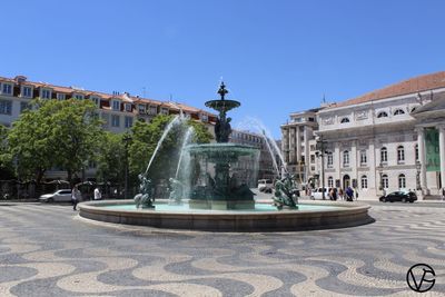 Fountain in city against clear sky