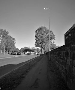 Street amidst trees against clear sky