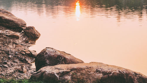 Rock formation by lake against sky