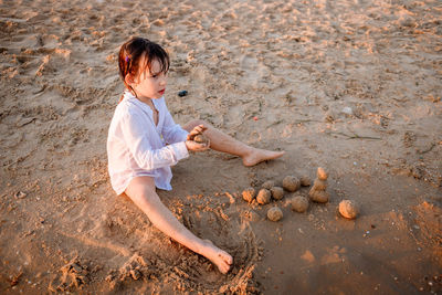 Full length of boy playing with sand at beach