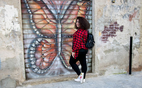 Woman standing against graffiti wall