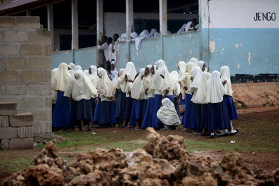 Rear view of people standing against the wall