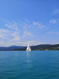 Sailboat sailing in sea against blue sky