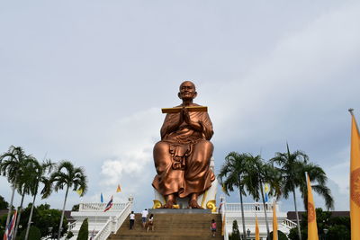 Low angle view of somdej toh statue at wat bot temple against sky