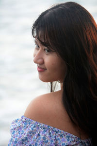 Close-up of young woman looking away against sea