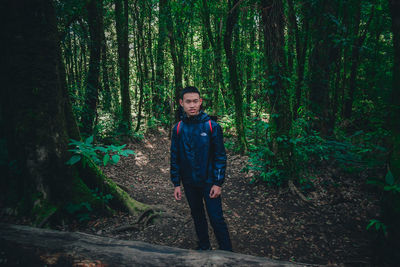 Portrait of man standing against trees in forest