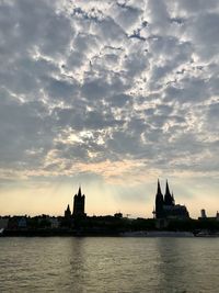 River amidst buildings against sky during sunset