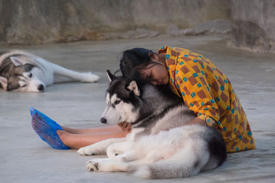 Woman embracing dog on footpath