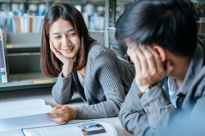 Portrait of smiling young woman using phone while sitting on table