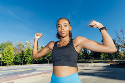 Young sportswoman flexing muscles in basketball court