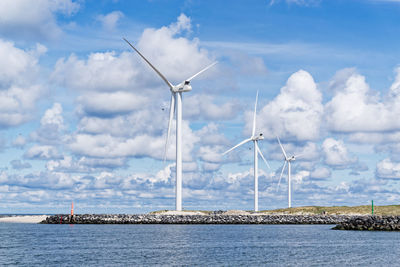 Three wind turbines on the shore against cloudy sky in hvide sande, denmark