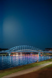 Illuminated bridge over river against sky at night