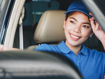 Smiling young woman looking away while sitting in car