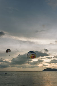 People paragliding over sea against sky