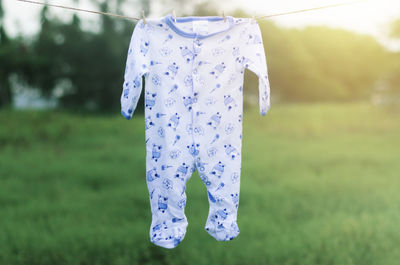Baby clothing hanging on clothesline against landscape