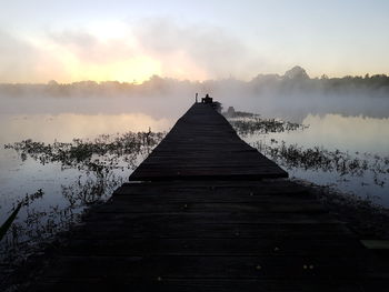 Pier over lake against sky during sunset