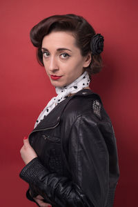 Portrait of young woman standing against red background