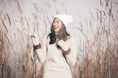 Young woman in warm clothing standing amidst plants on field