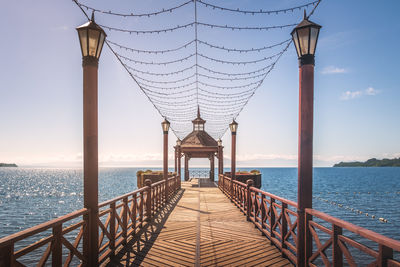 Pier over sea against sky during sunset