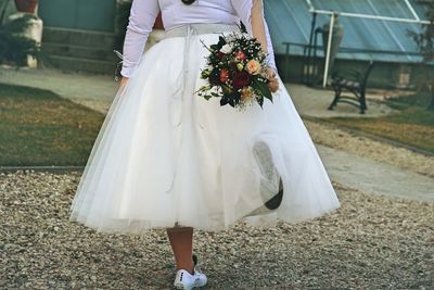 Midsection of bride with bouquet standing on land