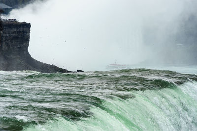 Waves splashing on sea against sky