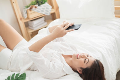 Midsection of woman using mobile phone while relaxing on bed