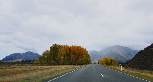 Road by mountains against sky