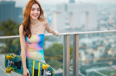 Portrait of smiling young woman standing against railing