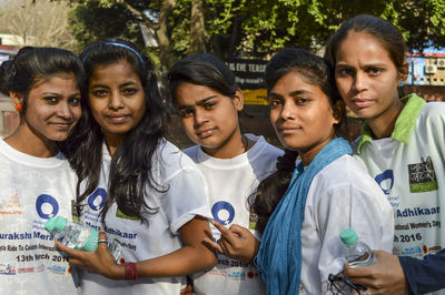 Portrait of teenage girl standing against people