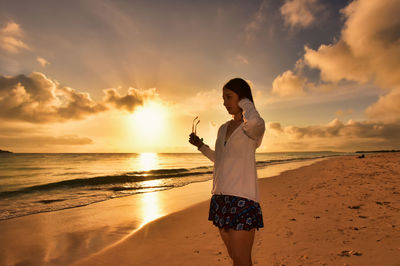 Full length of woman standing on beach during sunset