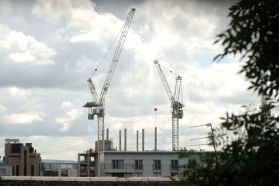 Cranes at construction site in city against sky