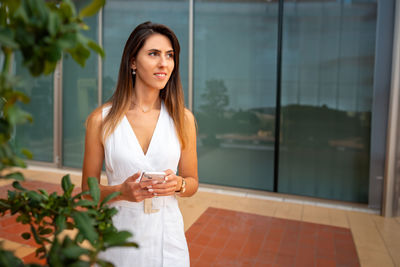 Portrait of young woman standing against wall