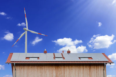 Low angle view of windmill on building against sky