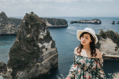 Young woman standing on rock by sea