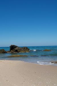 Scenic view of beach against clear blue sky