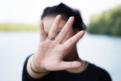 Young woman hiding face with hand by lake