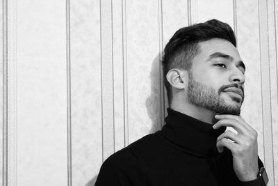 Portrait of young man looking away against wall