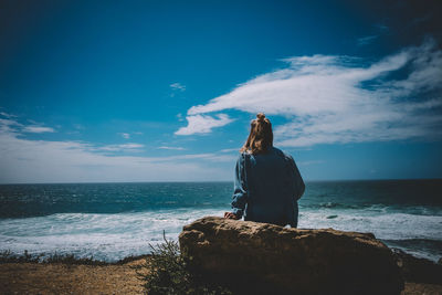 Rear view of woman standing on beach against sky