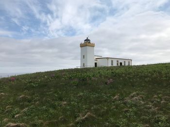 Lighthouse on field against sky