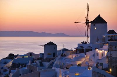 Town by sea against sky during sunset