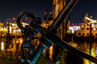 Close-up of illuminated railing against river in city at night