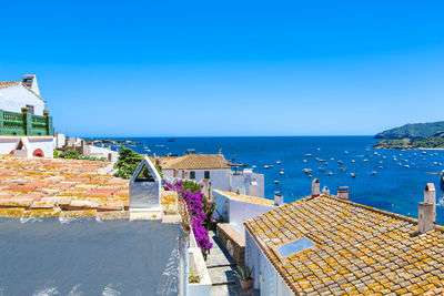 High angle view of buildings by sea against clear blue sky