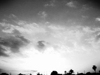 Low angle view of trees against cloudy sky