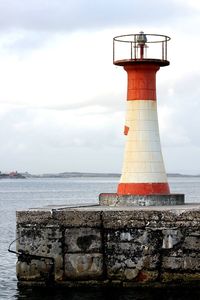 Lighthouse by sea against sky