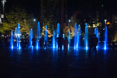 People dancing at illuminated city during night